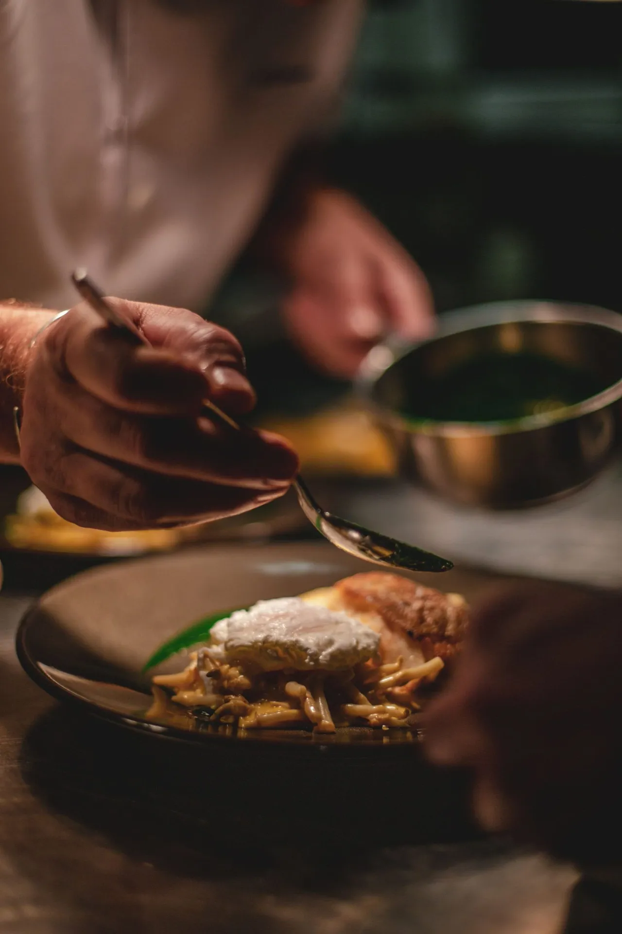 En cuisine, une main dépose la sauce sur l'assiette à la cuillère