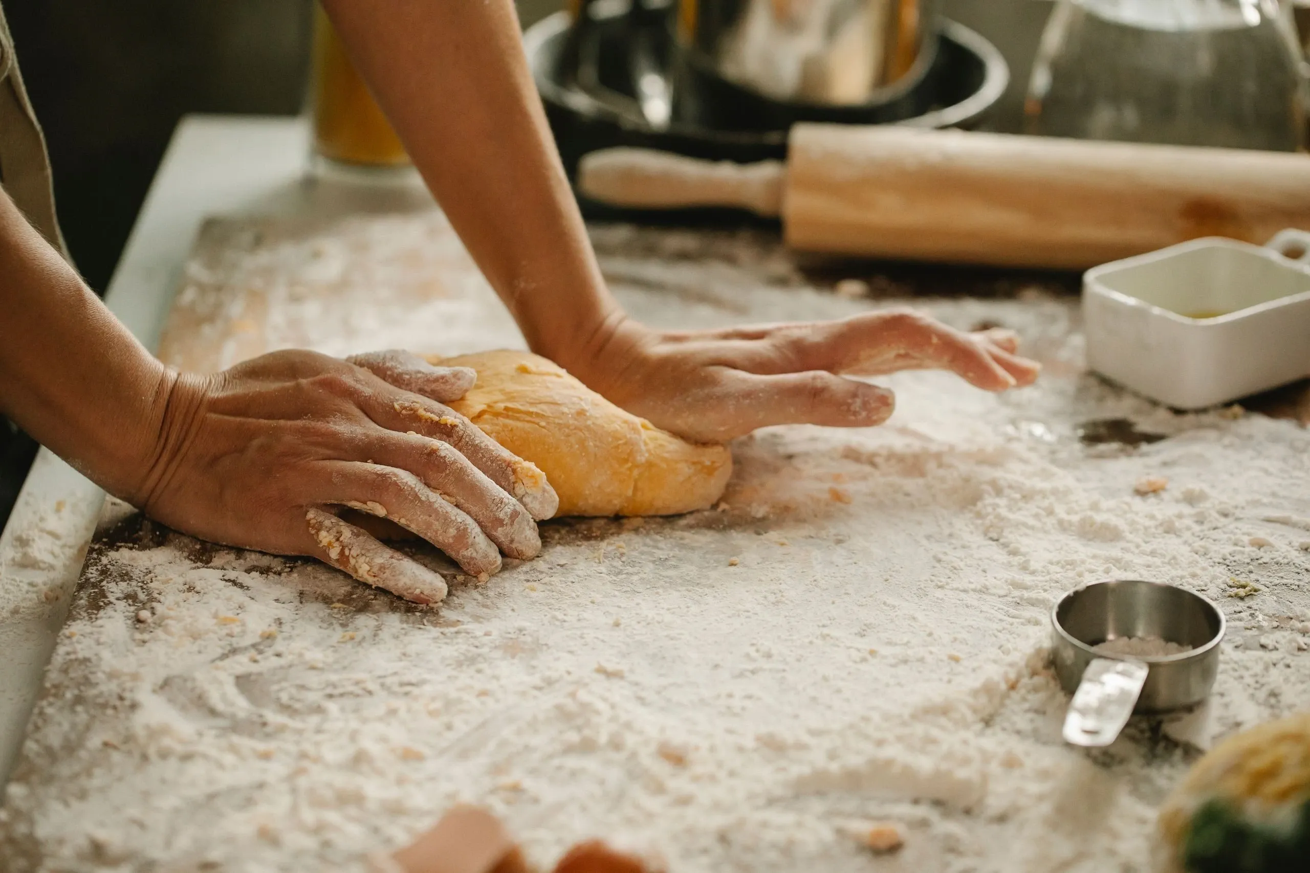 Les mains d'Inès travaillent une pâte sur un plan fariné