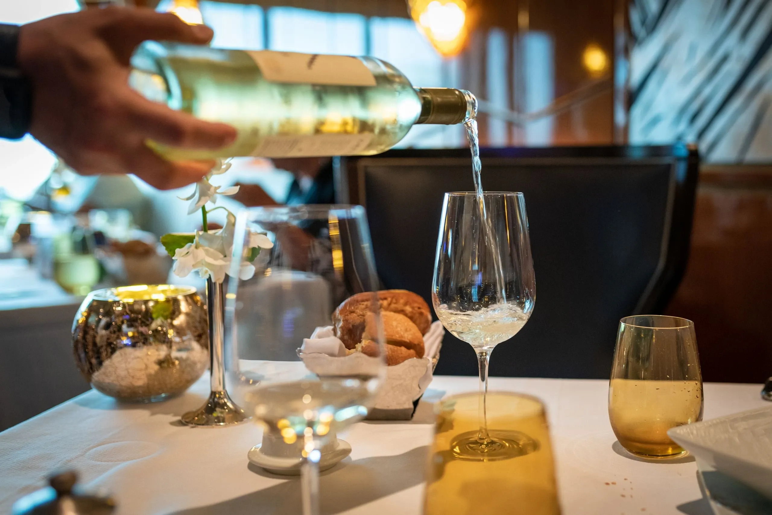 Un vin blanc versé dans un verre, sur une table nappée de blanc